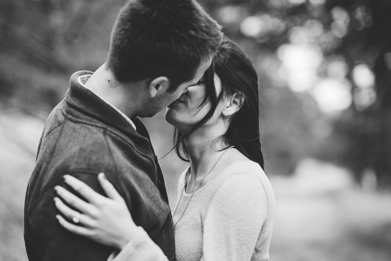 Evergreen engagement photography kissing couple in a forest black and white