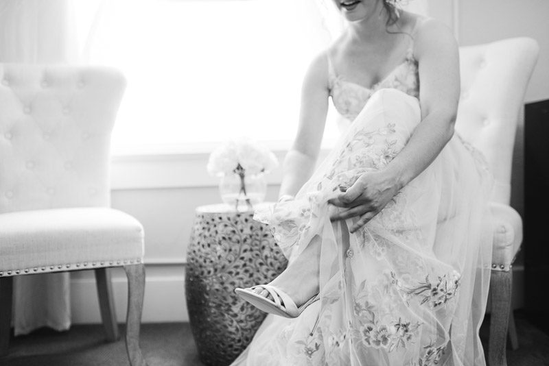 wedding bride putting on shoes black and white